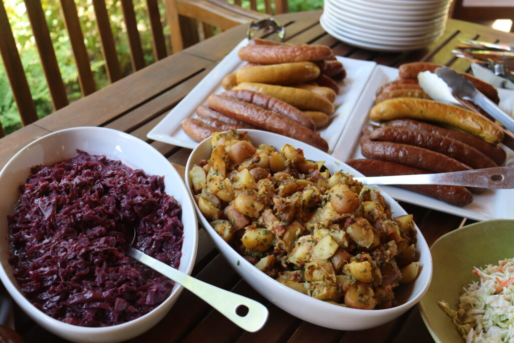 Westhofen Vineyard & Soil (1) German food is arranged on a table, including various sausages, potato salad, coleslaw, and cabbage.